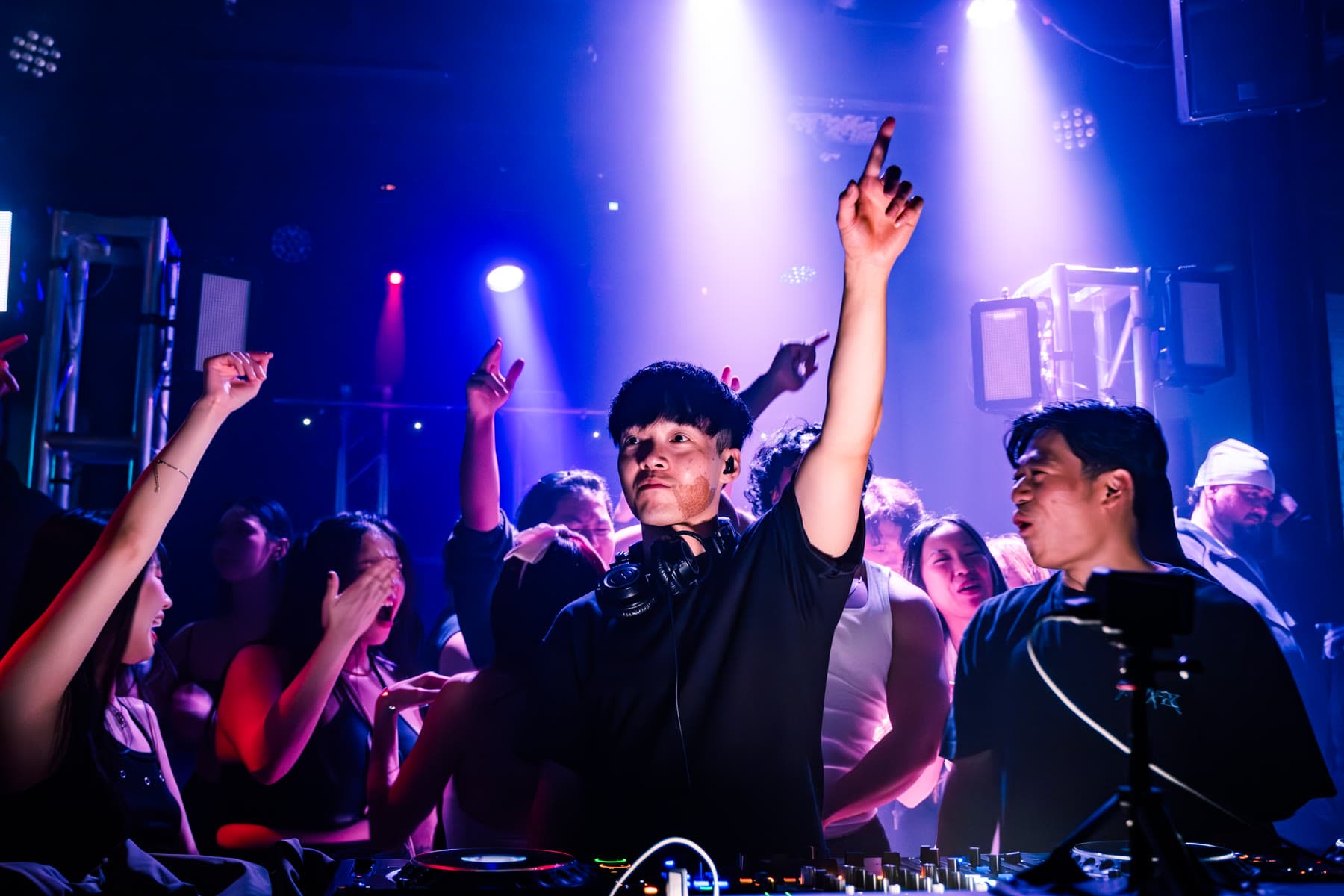 A crowd with hands in the air on a dark dance floor